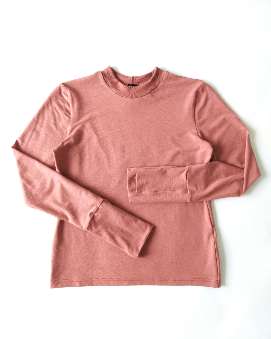 A flat lay of an organic comfy pink long sleeve shirt. Thumbs up Knit Long Sleeve Shirt in Terracotta Blush by September Archive. Photographed by Sheila Wong.