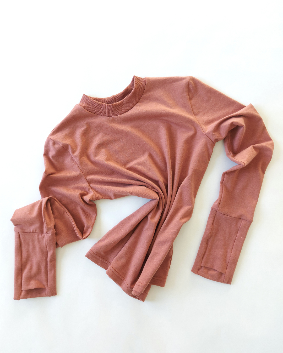 A flat lay of an organic comfy pink long sleeve shirt. Thumbs up Knit Long Sleeve Shirt in Terracotta Blush by September Archive. Photographed by Sheila Wong.