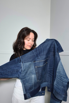 A woman holding up a cropped, oversized denim jacket made from multiple blue denim jeans, showing the layered patchwork construction and front pocket.
Upcycled denim jacket by September Archive Apparel. Canadian made denim jacket. One of a kind cropped denim jacket made in Vancouver, Canada. Photographed by Sheila Wong.